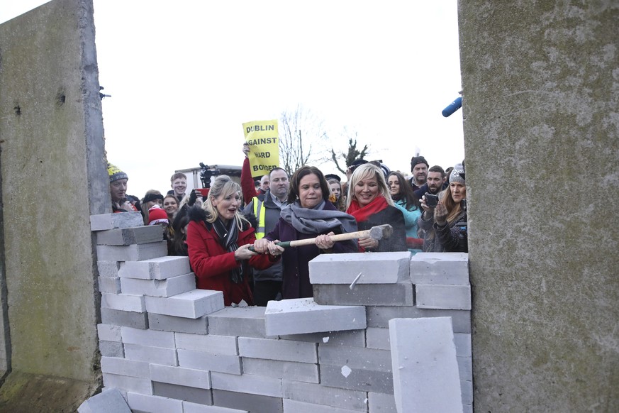 Sinn Fein Leader Mary Lou McDonald, centre, Martina Anderson, left, and Michelle O&#039;Neil, right, knock down a &#039;mock&#039; wall on the Northern Ireland/Republic of Ireland border, near Newry i ...