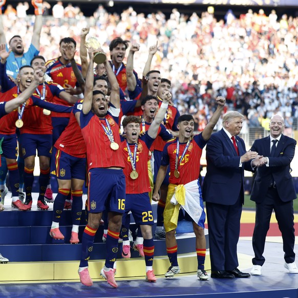 epa13122027 Rodri (C-R) and players of Spain celebrate with the World Cup Trophy as FIFA President Gianni Infantino (R) interacts with US President Donald J. Trump during the awards ceremony after the ...