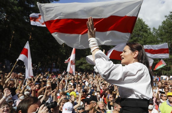 FILE In this file photo taken on Sunday, Aug. 2, 2020, Sviatlana Tsikhanouskaya, candidate for the presidential elections greets people waving old Belarus flags during a meeting to show her support ,  ...