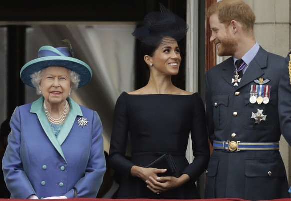 FILE - In this Tuesday, July 10, 2018 file photo Britain&#039;s Queen Elizabeth II, and Meghan the Duchess of Sussex and Prince Harry watch a flypast of Royal Air Force aircraft pass over Buckingham P ...