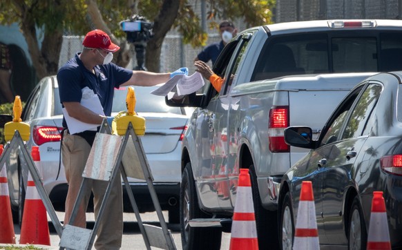 epa08353723 A Hialeah city worker is delivering printed Unemployment Benefits application to city&#039;s residents in their cars in Hialeah, Florida, USA, 09 April 2020. Hundreds of residents lined up ...