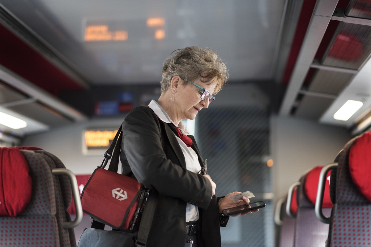 A train conductor of the Swiss Federal Railways checks passenger's tickets on a train travelling from Zurich to Lucerne, Switzerland, on March 20, 2017. (KEYSTONE/Christian Beutler)