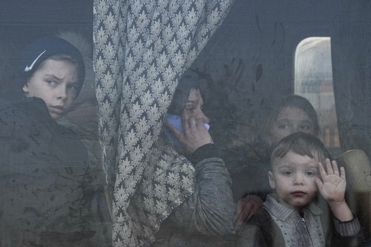 FILE - Internally displaced people look out from a bus at a refugee center in Zaporizhia, Ukraine, Friday, March 25, 2022. Quantifying the toll of Russia?s war in Ukraine remains an elusive goal a yea ...