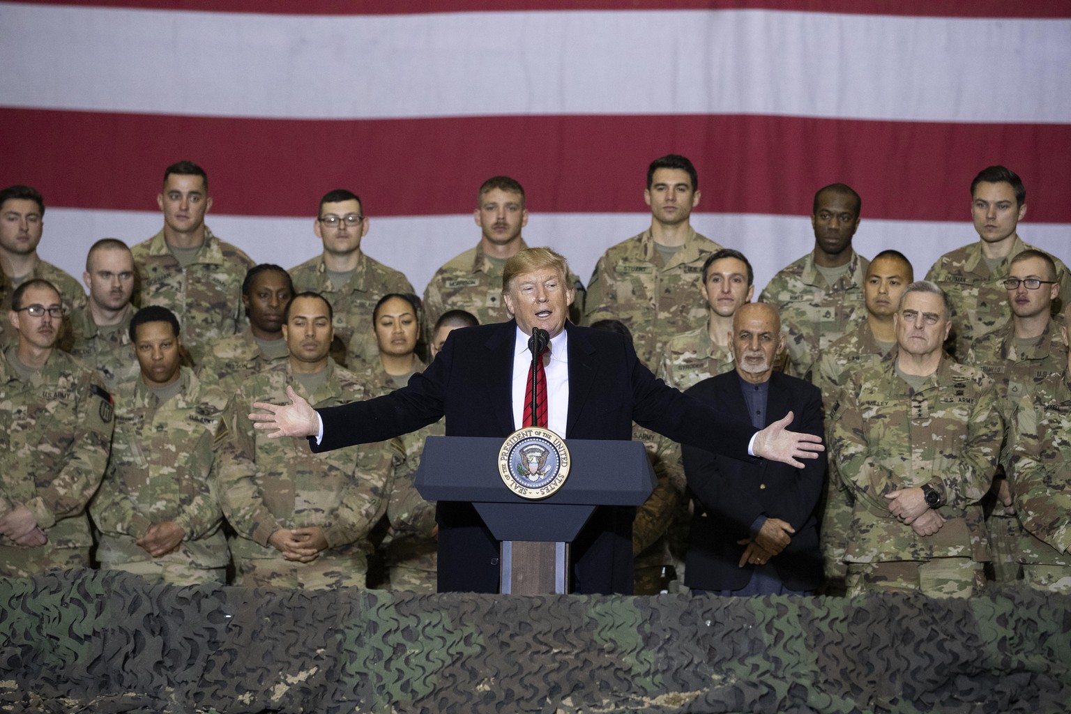 FILE - In this Nov. 28, 2019 file photo, President Donald Trump, center, with Afghan President Ashraf Ghani and Joint Chiefs Chairman Gen. Mark Milley, behind him at right, addresses members of the mi ...
