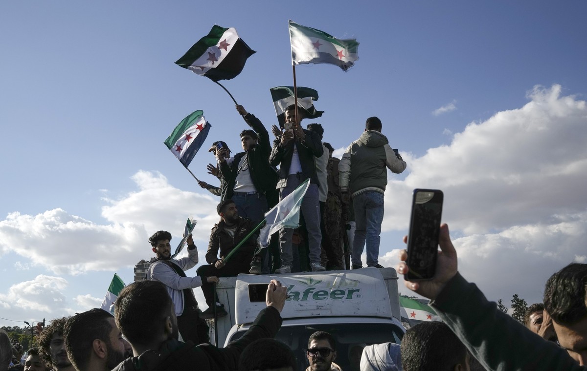 Syrians wave "revolutionary" Syrian flags during a celebratory demonstration following the first Friday prayers since Bashar Assad's ouster, in Damascus' central square, Syria, Fri ...
