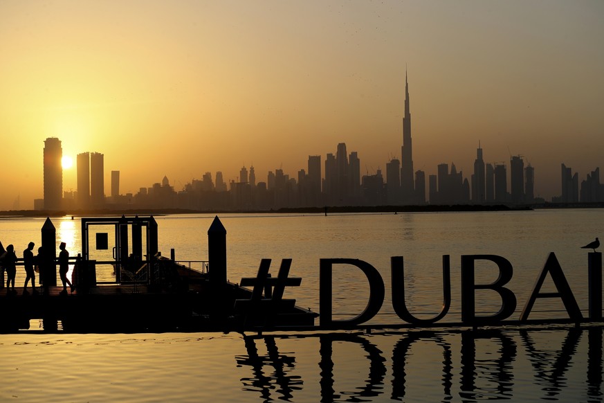 People enjoy the sunset with the view of city skyline and the world tallest tower, Burj Khalifa, in Dubai, United Arab Emirates, Friday, Jan.29, 2021. (AP Photo/Kamran Jebreili)