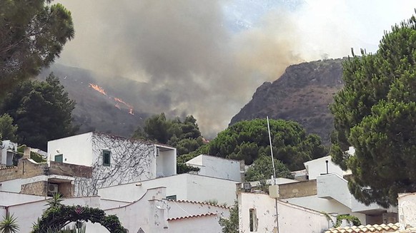 In this Wednesday, July 12, 2017 photo, a fire burns behind a tourist resort which was then successfully evacuated, in the Sicilian area of San Vito Lo Capo, near Trapani, southern Italy. Wildfires fu ...