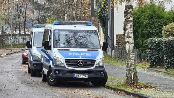 23.11.2023, Nordrhein-Westfalen, Bochum: Einsatzfahrzeuge der Polizei stehen bei einer Razzia in Bochum-Weitmar auf der Stra