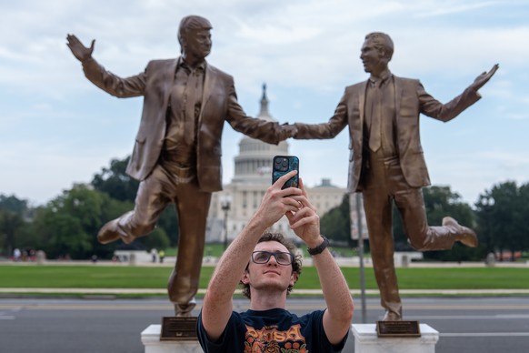 A person takes a selfie in front of a work of protest art representing President Donald Trump and Jeffrey Epstein on the National Mall near the Capitol, Tuesday, Sept. 23, 2025, in Washington. (AP Pho ...