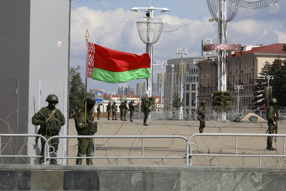 Belarusian Internal Ministry troops, one of soldiers holding a Belarusian State flag, block an area to prevent of opposition rally protesting the official presidential election results in Minsk, Belar ...