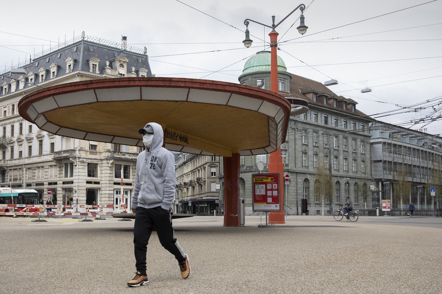 Eine Person mit einer Schutzmaske geht ueber den Zentralplatz waehrend der Coronavirus Pandemie, am Sonntag, 29. Maerz 2020 in Biel. (KEYSTONE/Peter Klaunzer)