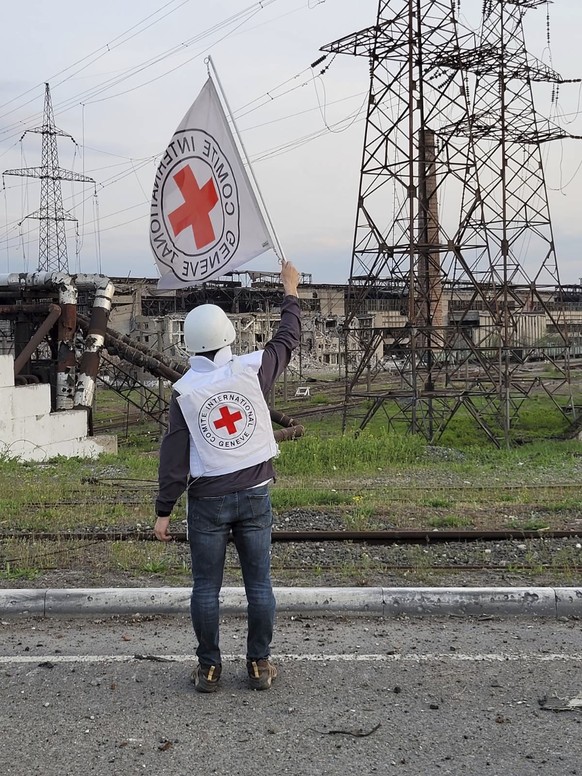 In this image provided by the International Committee of the Red Cross, a Red Cross official waves a white flag while approaching the Azovstal steelworks in Mariupol, Ukraine, Sunday, May 1, 2022. A l ...