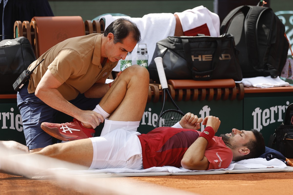 Serbia's Novak Djokovic receives medical assistance for his right knee during his fourth round match of the French Open tennis tournament against Argentina's Francisco Cerundolo at the Rolan ...