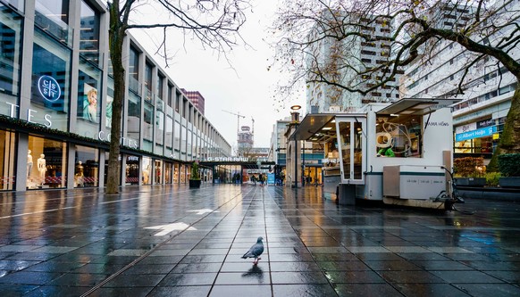 epa09650285 A pigeon walks through a deserted shopping are during a coronavirus lockdown in Rotterdam, the Netherlands, 19 December 2021. The Netherlands enforced a hard lockdown from 19 December 2021 ...