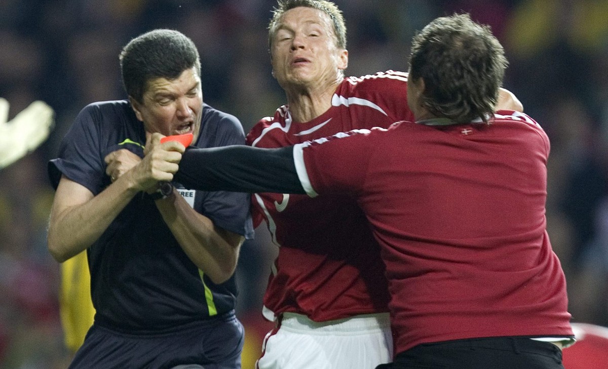 FILE - In this Saturday June 2, 2007 file photo Denmark's Michael Gravgaard, center, tries to intervene as Danish supporter Ronni Noervig attacks referee Herbert Fandel , left, for giving Sweden  ...