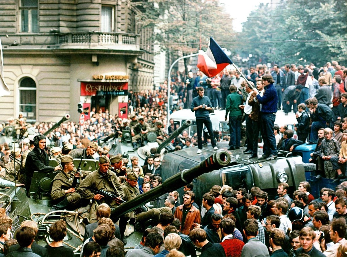 Prager Buerger mit tschechischer Flagge stehen auf einem umgestuerzten Wagen vor einem sowjetischen Panzer am 21. Aug. 1986 in Prag. Als in der Nacht zum 21. August 1968 sowjetische Panzer den "P ...