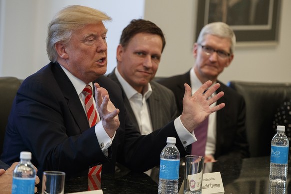 Apple CEO Tim Cook, right, and PayPal founder Peter Thiel, center, listen as President-elect Donald Trump speaks during a meeting with technology industry leaders at Trump Tower in New York, Wednesday ...