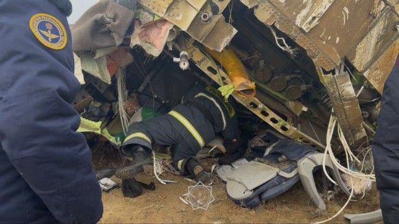 epa11792902 A handout photo made available by the press service of the Ministry for Emergency Situations of Kazakhstan shows emergency specialists working at the crash site of a passenger plane near A ...