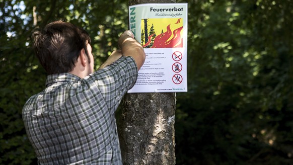 Revierfoerster Christoph Hitz befestigt ein Schild mit der Aufschrift "Feuerverbot Waldbrandgefahr" im Wald von Greppen am Donnerstag, 26. Juli 2018. Wegen der anhaltenden Trockenheit haben  ...
