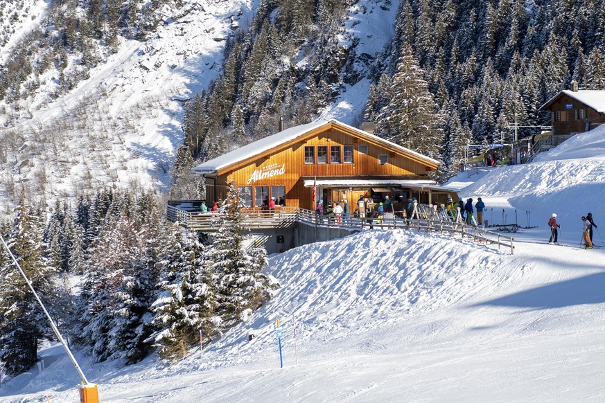 Skifahrer mit Schutzmaske ums Restaurant Allmend, am Freitag, 8. Januar 2021, im Skigebiet Grindelwald - Wengen. Die Berner Skigebiete bleiben trotz Coronavirus geoeffnet, mit reduzierter Transportkap ...