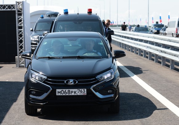 Russian President Vladimir Putin, right, drives a Lada Aura car, front, as he arrives to attend a ceremony to open the Northern Tver Bypass on the M-11 Neva highway and the Togliatti Bypass in Samara  ...