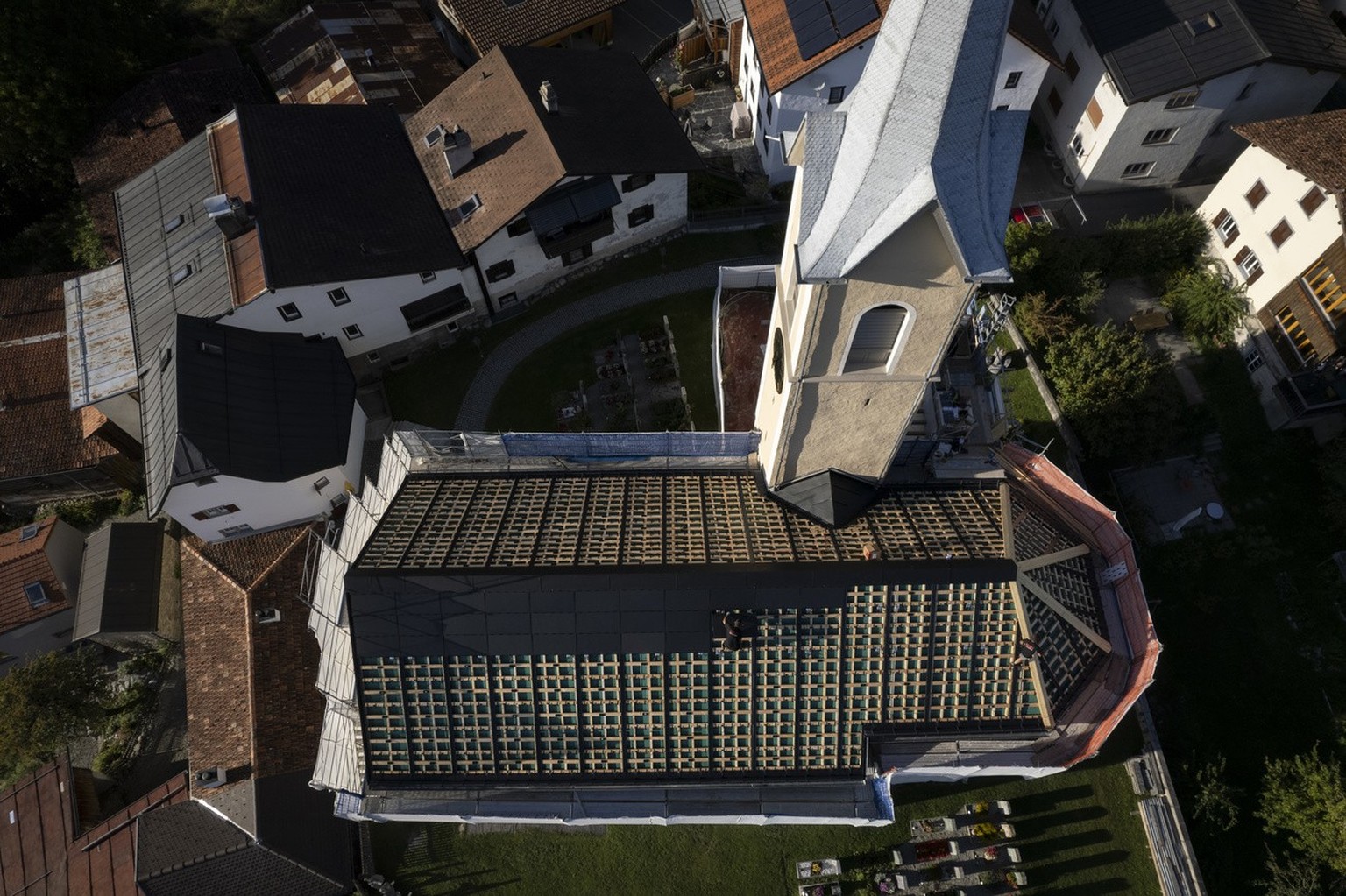 Arbeiter montieren Solarpanels auf dem Dach der historischenKirche, aufgenommen am Dienstag, 19. September 2023, in Trin. (KEYSTONE/Gian Ehrenzeller)