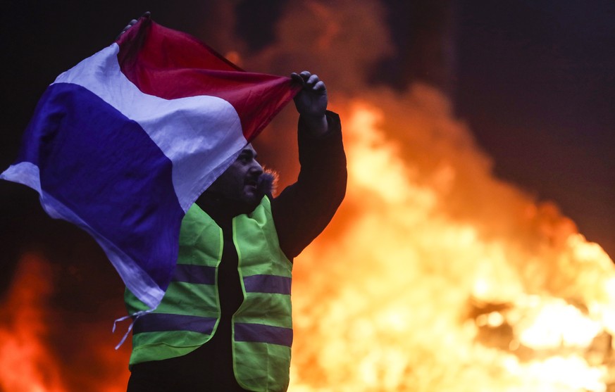 epa07201679 Cars burn, while protesters wearing yellow vests (gilets jaunes) clash with riot police near the Arc de Triomphe as part of a demonstration over high fuel prices on the Champs Elysee in Pa ...