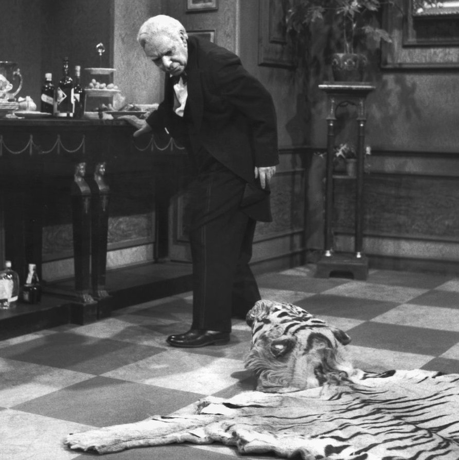 Butler James, played by Freddie Frinton, looks disapprovingly at the tiger skin lying on the floor, which is a constant tripping hazard on the way to and from the counter.  (KEYSTONE/epa/DPA/NDR/S ...