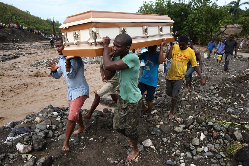 epaselect epa05572082 A group of people carry a coffin and try to cross the river La Digue, after the colapse of the only bridge that connects to the south after the passing of hurricane Matthew in th ...