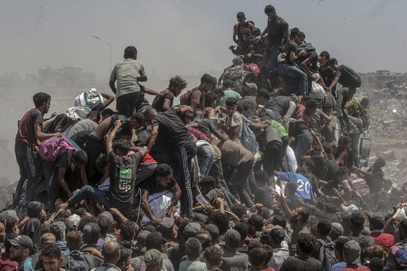 epa12265743 Internally displaced Palestinians try to grab bags of flour from an aid truck near a food distribution point in Zikim, northern Gaza Strip, 27 July 2025. The Israeli army declared a &#039; ...