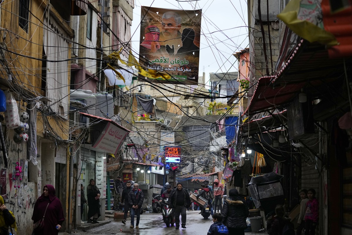Palestinians walk under a poster that shows Yahya Sinwar, head of Hamas in Gaza, on a street inside the Bourj al-Barajneh Palestinian refugee camp, south of Beirut, Lebanon, Monday, Feb. 5, 2024. Ther ...