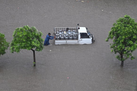 epa10727935 A man pushes a mini truck through a flooded area after heavy rains in Lahore, Pakistan, July 05, 2023. The Pakistan Meteorological Department (PMD) has forecast monsoon rains for most...