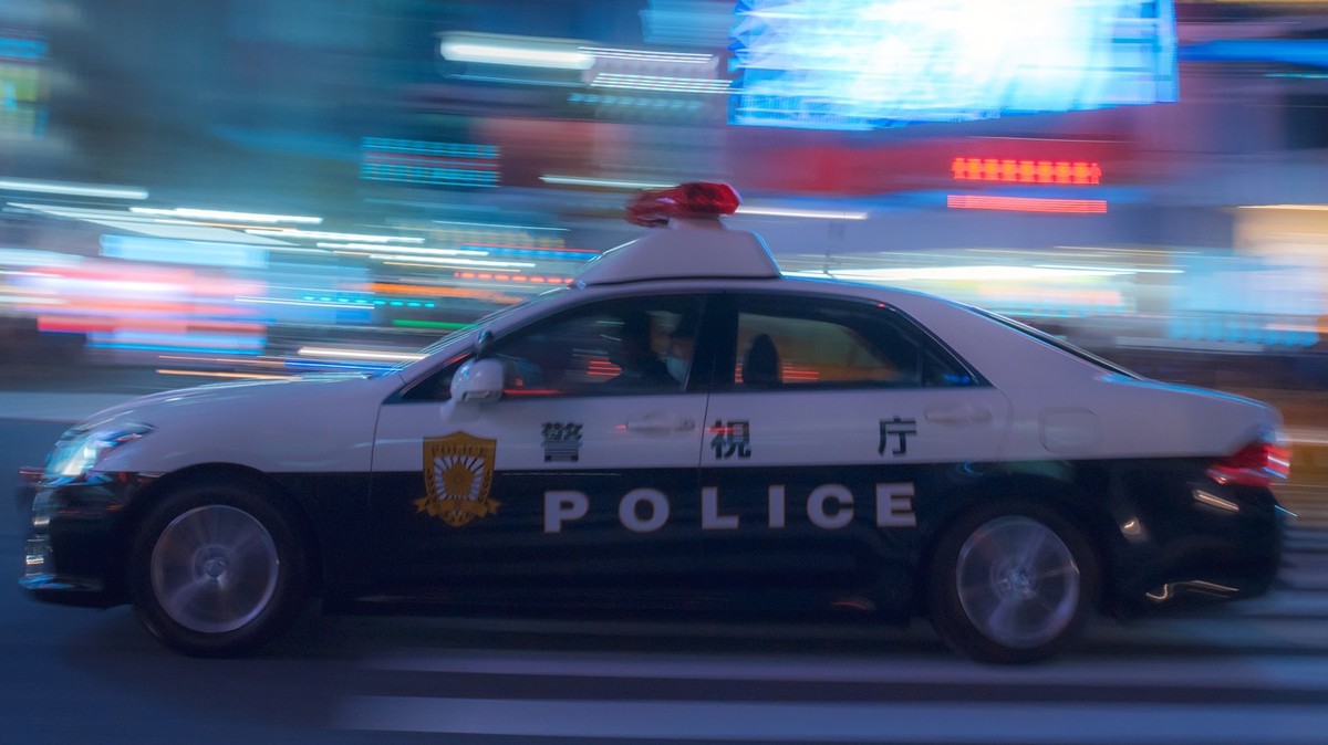 Shibuya, TOKYO, JAPAN - December 3rd, 2018. Tokyo Metropolitan police car at the very famous Shibuya Crossing, Tokyo by night panning shot of a Metropolitan police car at the very famous Shibuya Cross ...