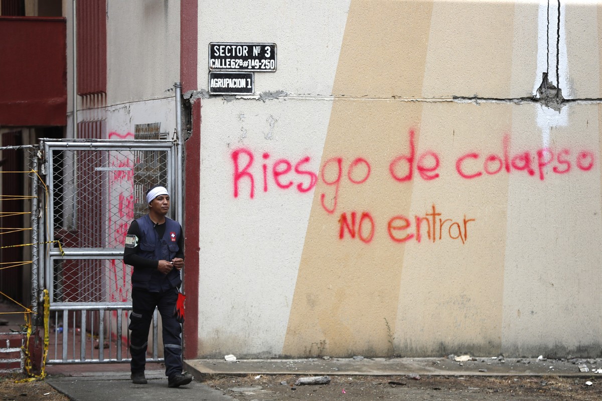 epa13176382 A rescue worker walks past damaged residential buildings at risk of collapse in the Chiminangos neighborhood of Cali, Colombia, 17 August 2026. A 7.4-magnitude earthquake struck Colombia o ...