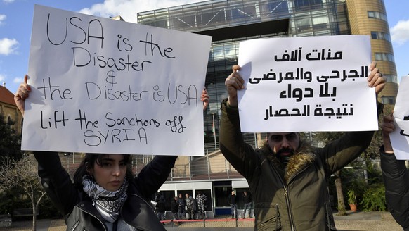 epa10454872 Supporters of the Syrian Social Nationalist Party carry placards and party flags during a protest to demand the lifting of the sanctions and the Caesar Act on Syria in front of the United  ...