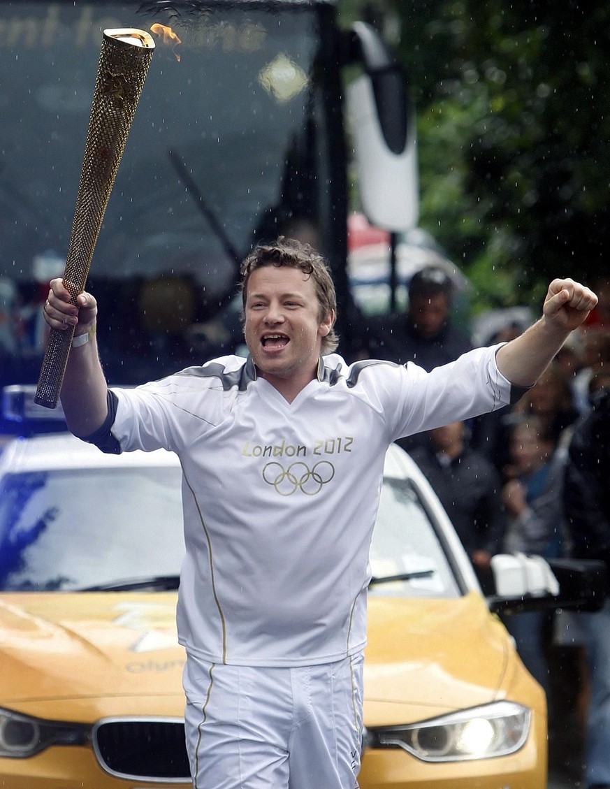 This photo made available by LOCOG shows torchbearer 063 Jamie Oliver carrying the Olympic Flame on the Torch Relay leg between Newport and Saffron Walden, Wales on the Day 50 of the Torch Relay Satur ...