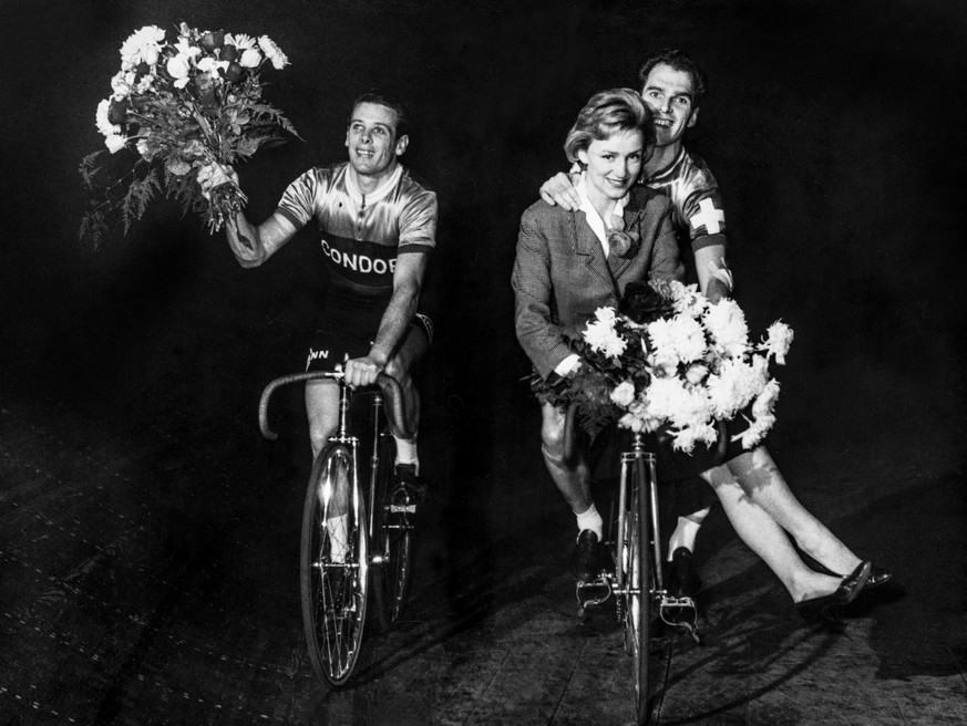 Die Fernsehmoderatorin Heidi Abel faehrt mit den beiden Siegern des 7. Sechstagerennens in Zuerich Reginald Arnold, links, und Walter Bucher, rechts, eine Ehrenrunde, aufgenommen im November 1959. (KE ...