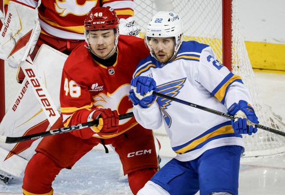 St. Louis Blues' Pius Suter, right, is checked by Calgary Flames' Hunter Brzustewicz during the first period of an NHL hockey game in Calgary on Wednesday, March 18, 2026. (Jeff McIntosh/The ...