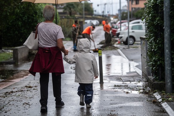 epa10823491 Pedestrians watch workmen clean a street after heavy rainfall in Solduno, Switzerland, 27 August 2023. The canton Tessin, the Italian part of Switzerland, got a lot of rain since late 25 A ...
