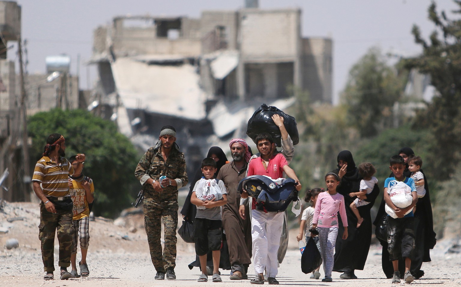 Syria Democratic Forces (SDF) fighters walk with people that fled their homes due to clashes between Islamic State fighters and Syria Democratic Forces (SDF) towards safer parts of Manbij, in Aleppo G ...