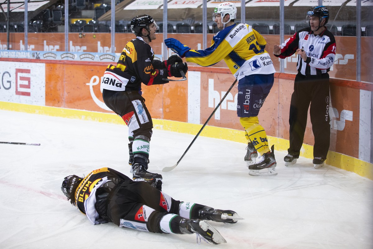 Berns Eric Blum liegt nach einem Check von Davos' Fabrice Herzog, rechts, auf dem Eis, im Eishockey Meisterschaftsspiel der National League zwischen dem SC Bern und HC Davos, am Sonntag, 14. Febr ...