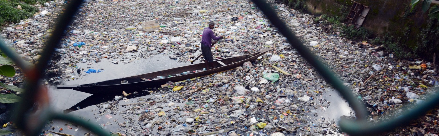 epaselect epa07988066 A ragpicker steers his boat to collect plastic bottles and other recyclable items from the polluted water of the Bharalu River as school children look on, in Guwahati, India, 11  ...