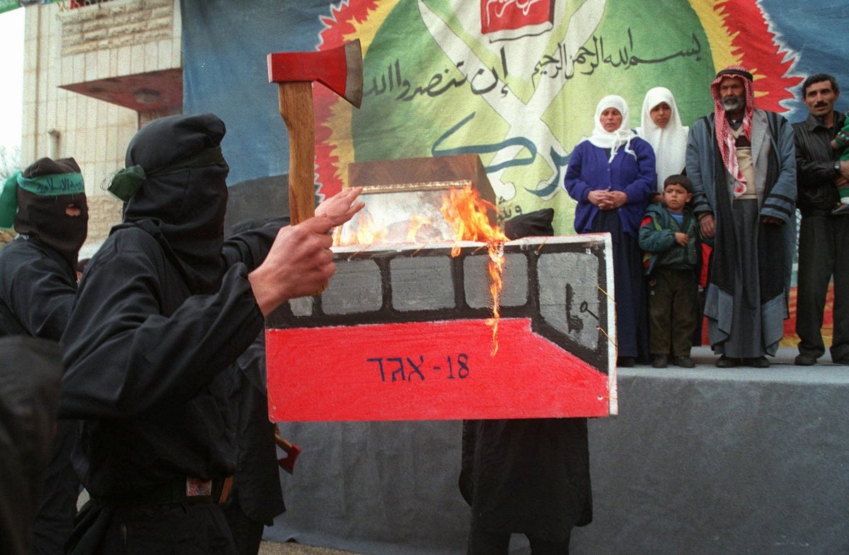 Masked members of the Islamic militant group Hamas burn an effigy of a number eighteen Israeli bus during a demonstration held at Hebron's Polytechnic College Monday Jan. 5, 1998. The demonstrati ...