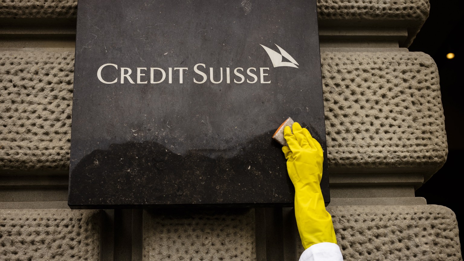 epa10619151 An activist of Scientist Rebellion cleans symbolically the sign at the entrance of the Swiss Bank Credit Suisse at Paradeplatz during a protest against fossil fuel investments, in Zurich,  ...