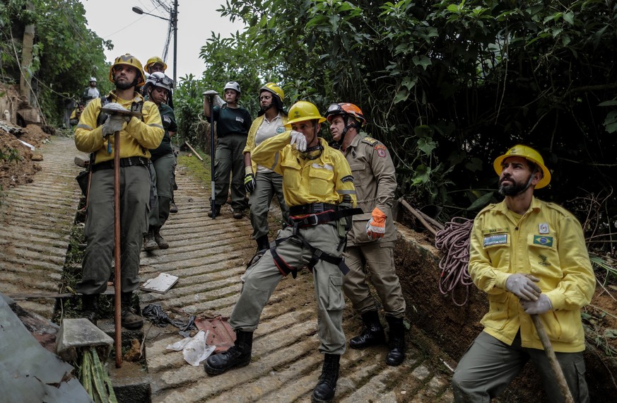 epa09763779 Firefighters observe the rescue of a person victim of heavy rains, in Petropolis, Brazil, 16 February 2022. Petropolis was devastated by the rains that have left more than fifty dead, thou ...