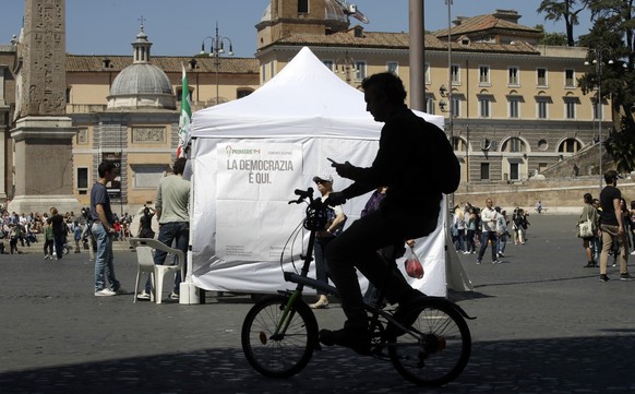 A man on a bicycle rides past a makeshift gazebo set up around the country for the Democratic party&#039;s primary elections, in Rome Sunday, April 30, 2017. Italians are voting for a new leader of th ...