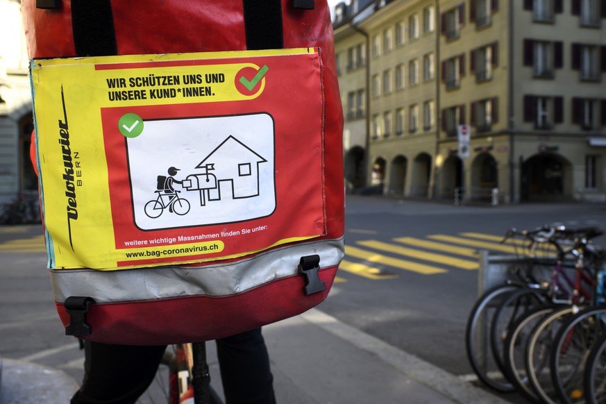 Die Tasche eines Fahrradkuriers mit Verhaltensregeln gegen die Ansteckung mit dem Coronavirus, fotografiert waehrend der Coronavirus (Covid-19) Pandemie, am Dienstag, 24. Maerz 2020 in Bern. (KEYSTONE ...
