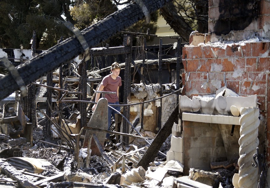 epa06257852 Jordan Williamson surveys damage to his home after it was destroyed by the Canyon Fire 2 in Anaheim Hills, California, USA, 10 October 2017. 24 structures were destroyed and 7,500 acres bu ...