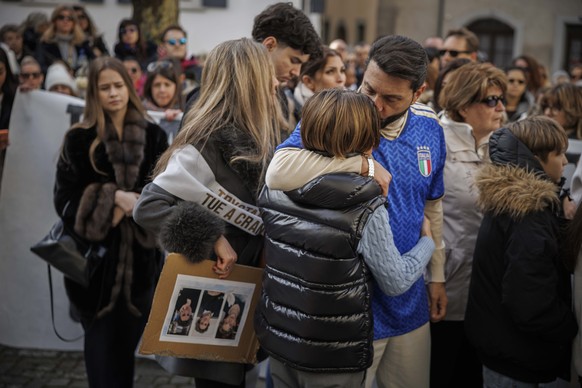 The father of a victim holds a child in her arms as approximately a thousand people gathered to pay tribute to the victims of the tragedy in Crans-Montana and to call for "justice and truth" ...