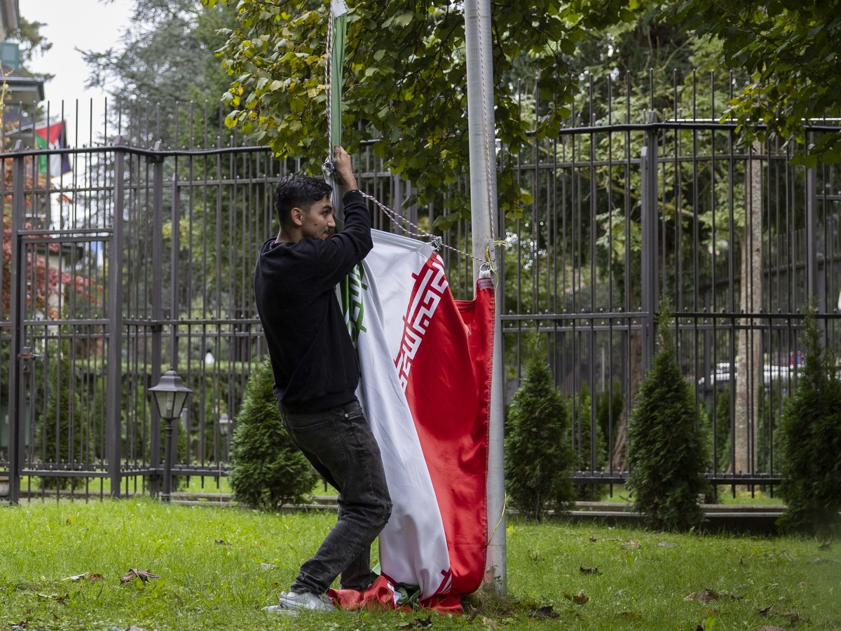 epa10217604 A protester takes down the Iranian flag on the ground of the Iranian embassy during the global protest against the Iranian regime in front of the Iranian embassy in Bern, Switzerland, 01 O ...